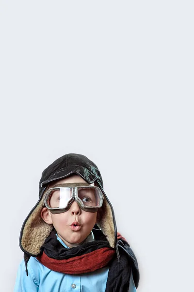 Niño con camisa azul, gafas de piloto, sombrero y bufanda sobre un fondo claro — Foto de Stock