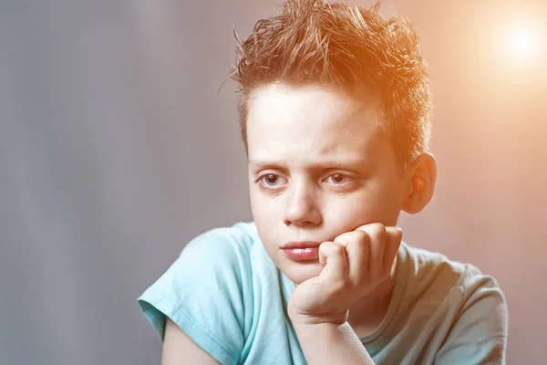 En pojke i en ljus t-shirt kränkt och gråter — Stockfoto