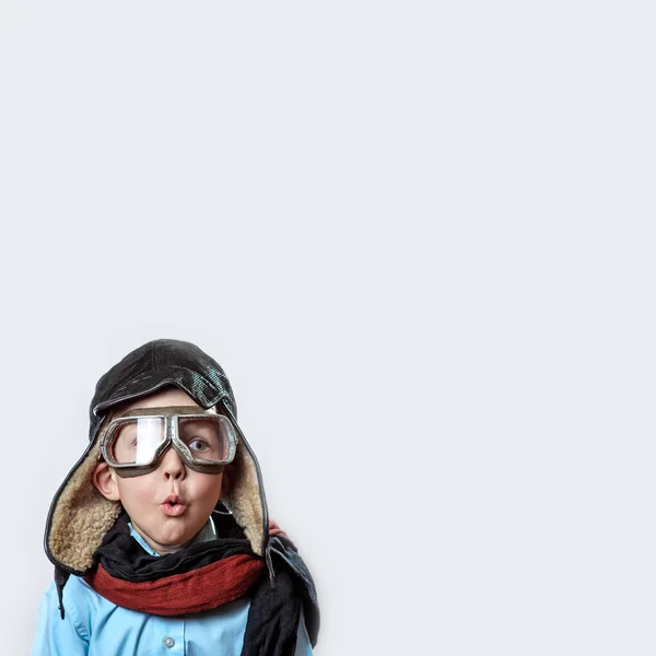 Niño con camisa azul, gafas de piloto, sombrero y bufanda sobre un fondo claro — Foto de Stock