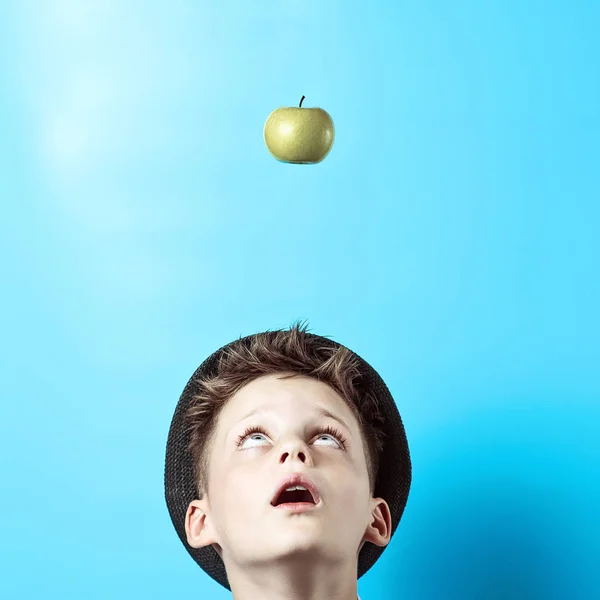 Chico sorprendido en una camisa ligera mira hacia arriba. Allí en él cae la manzana verde, como símbolo de grandes ideas — Foto de Stock