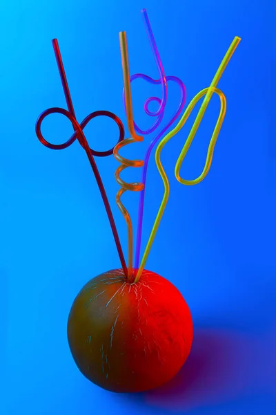Un brillante tubi da cocktail colorati bloccati in un melone su uno sfondo blu — Foto Stock
