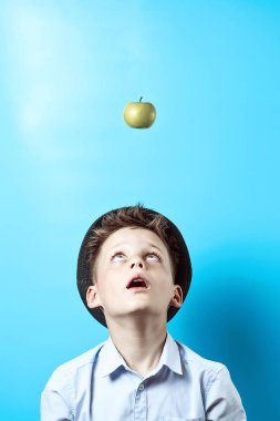 Hafif gömlekli sürpriz çocuk yukarı bakıyor. Orada onu büyük fikirlerin bir sembolü olarak, yeşil Apple düşüyor