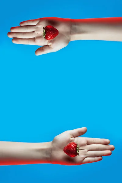 Collage af lyse saftige jordbær i hånden på blå baggrund - Stock-foto