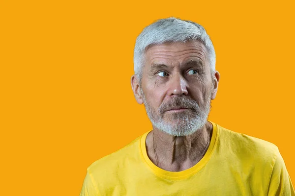 Retrato de hombre sorprendido y curioso de pelo gris con barba sobre fondo amarillo — Foto de Stock