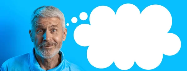 Portrait of surprised and curious gray-haired man with a beard on a blue background — Stock Photo, Image