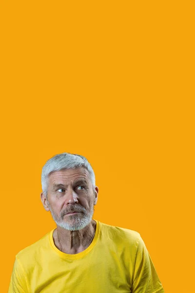 Retrato de homem surpreso e curioso de cabelos grisalhos com uma barba em um fundo amarelo — Fotografia de Stock
