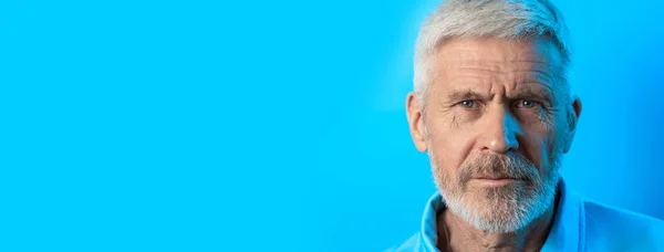Ritratto di un uomo dai capelli grigi accigliati con la barba su sfondo blu — Foto Stock
