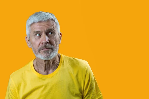 Ritratto di un uomo sorpreso e curioso dai capelli grigi con la barba su sfondo giallo — Foto Stock