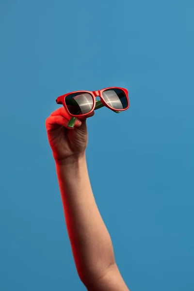 Farbige Sonnenbrille in Armlänge auf blauem Hintergrund — Stockfoto
