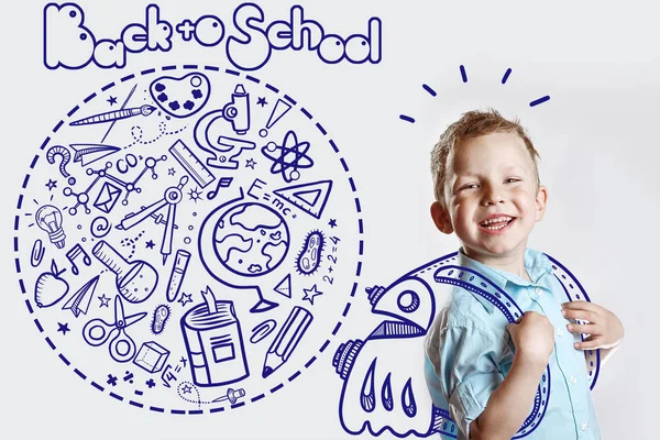 밝은 셔츠 를 입은 행복 한 어린이가 처음으로 학교에 간다. 그 의 뒤에는 다양 한 성화를 담은 배낭이 놓여 있다 — 스톡 사진
