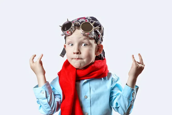 Niño en camisa azul, bufanda roja, gafas de ciclista y bandana sobre fondo claro — Foto de Stock