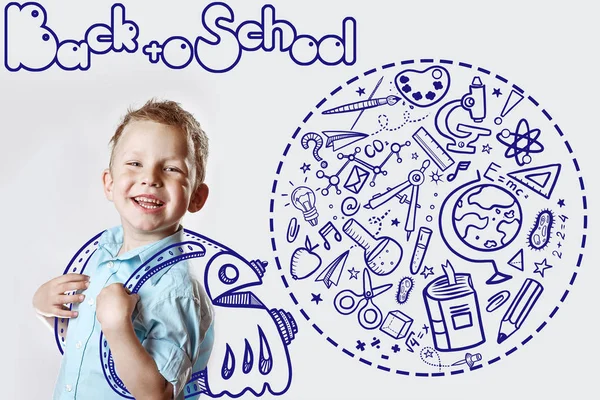 밝은 셔츠 를 입은 행복 한 어린이가 처음으로 학교에 간다. 그 의 뒤에는 다양 한 성화를 담은 배낭이 놓여 있다 — 스톡 사진
