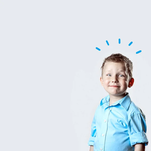 Um menino feliz sorridente em camisa azul no fundo claro — Fotografia de Stock