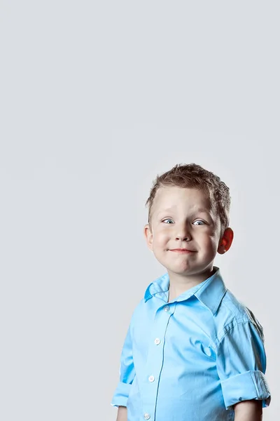 Um menino feliz sorridente em camisa azul no fundo claro — Fotografia de Stock