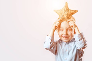 beyaz bir arka plan üzerinde bir denizyıldızı tutan hafif bir t-shirt çocuk