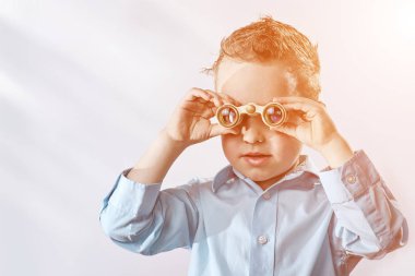 hafif bir arka plan üzerinde dürbün ile bakarak hafif bir gömlek çocuk