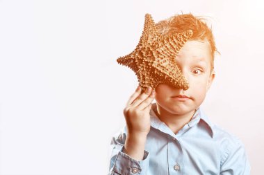 beyaz bir arka plan üzerinde bir denizyıldızı tutan hafif bir t-shirt çocuk