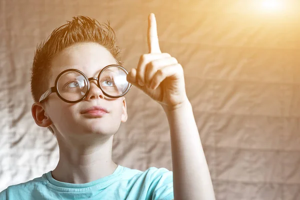 Хлопчик у легкій футболці і круглих окулярах підняв свій індексний палець у нього була ідея — стокове фото