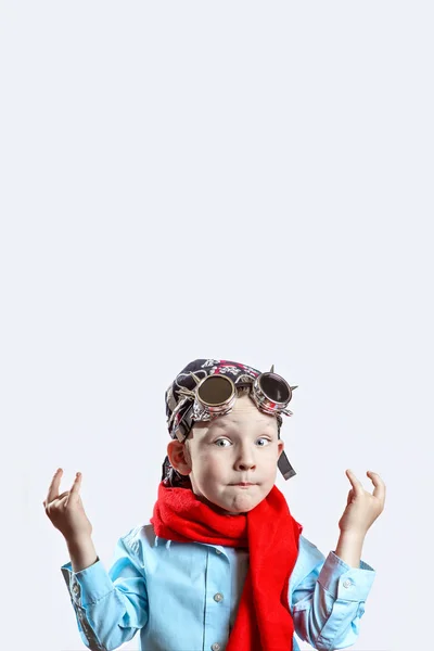 Niño en camisa azul, bufanda roja, gafas de ciclista y bandana sobre fondo claro — Foto de Stock