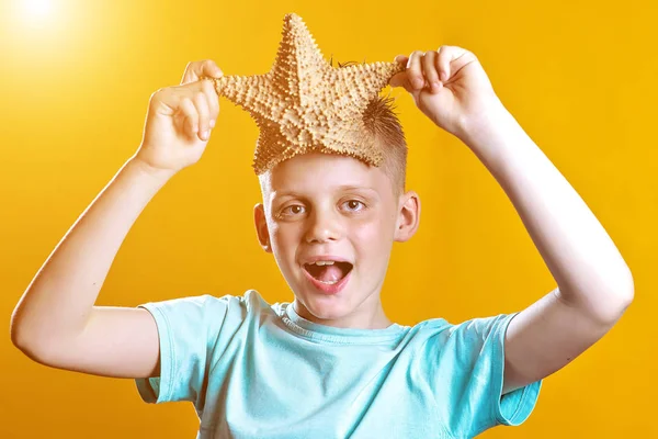 En dreng i en let t-shirt med en søstjerne på gul baggrund - Stock-foto