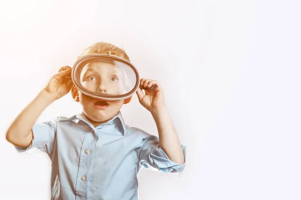 Un niño sorprendido en una camisa azul con una máscara submarina para nadar sobre un fondo claro — Foto de Stock