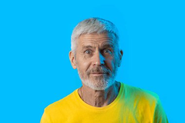 mavi bir arka plan üzerinde sakallı sürpriz ve meraklı gri saçlı adam portresi