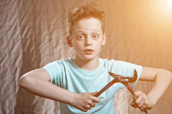 En dreng med en skruenøgle og overraskede øjne reparationer - Stock-foto