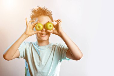 mavi bir t-shirt çocuk gözlerine iki yeşil elma koymak ve ışık arka planda gülüyor