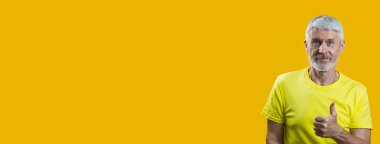 sakallı gri saçlı bir adamın portresi mavi arka planda iyi bir jest gösterir