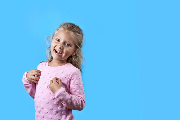 En söt glad tjej med gropar på hennes kinder och lockigt hår ler på blå bakgrund — Stockfoto