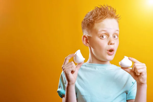 Munter dreng i en let t-shirt med et brudt æg på en farvet baggrund - Stock-foto