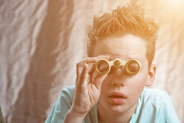 Overrasket teenager dreng følelsesmæssigt kigger gennem kikkert - Stock-foto