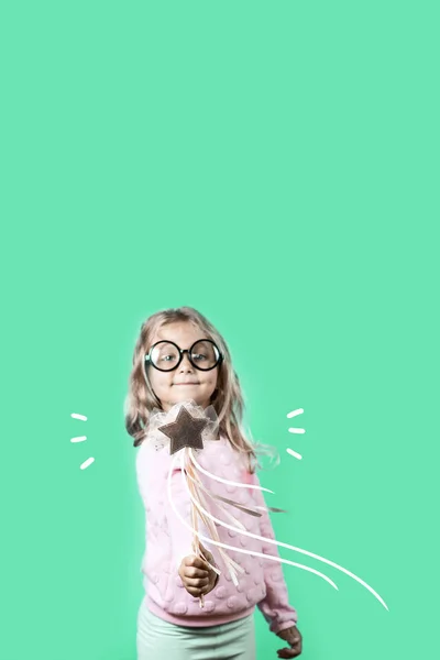 Flicka med glasögon och en trollstav säger en spell på grön bakgrund — Stockfoto