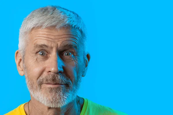 Retrato de hombre sorprendido y curioso de pelo gris con barba sobre fondo azul — Foto de Stock