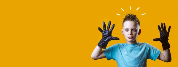 Здивований хлопчик в чорних рукавичках і синій футболці на жовтому фоні — стокове фото