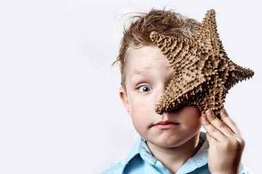 beyaz bir arka plan üzerinde bir denizyıldızı tutan hafif bir t-shirt çocuk