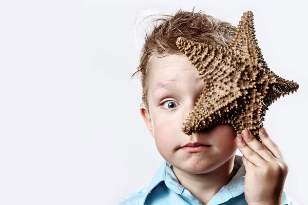 beyaz bir arka plan üzerinde bir denizyıldızı tutan hafif bir t-shirt çocuk