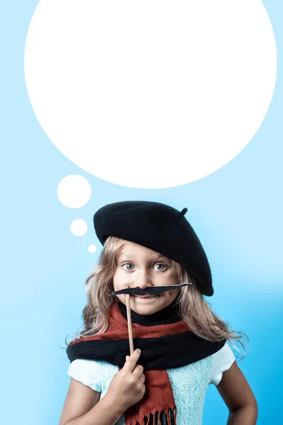 Sjov pige i sort baret, tørklæde og overskæg på en pind på blå baggrund - Stock-foto