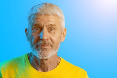 mavi bir arka plan üzerinde sakallı sürpriz ve meraklı gri saçlı adam portresi