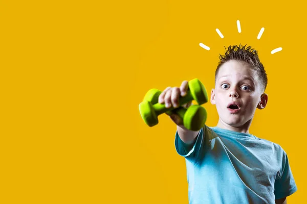 En dreng i en lys t-shirt med håndvægte på gul baggrund - Stock-foto