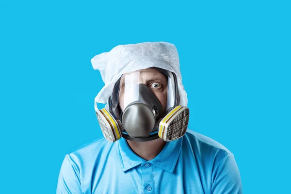 A man in a gas mask and a plastic bag on his head symbolizes the protection of the environment from pollution on blue background — Stock Photo, Image
