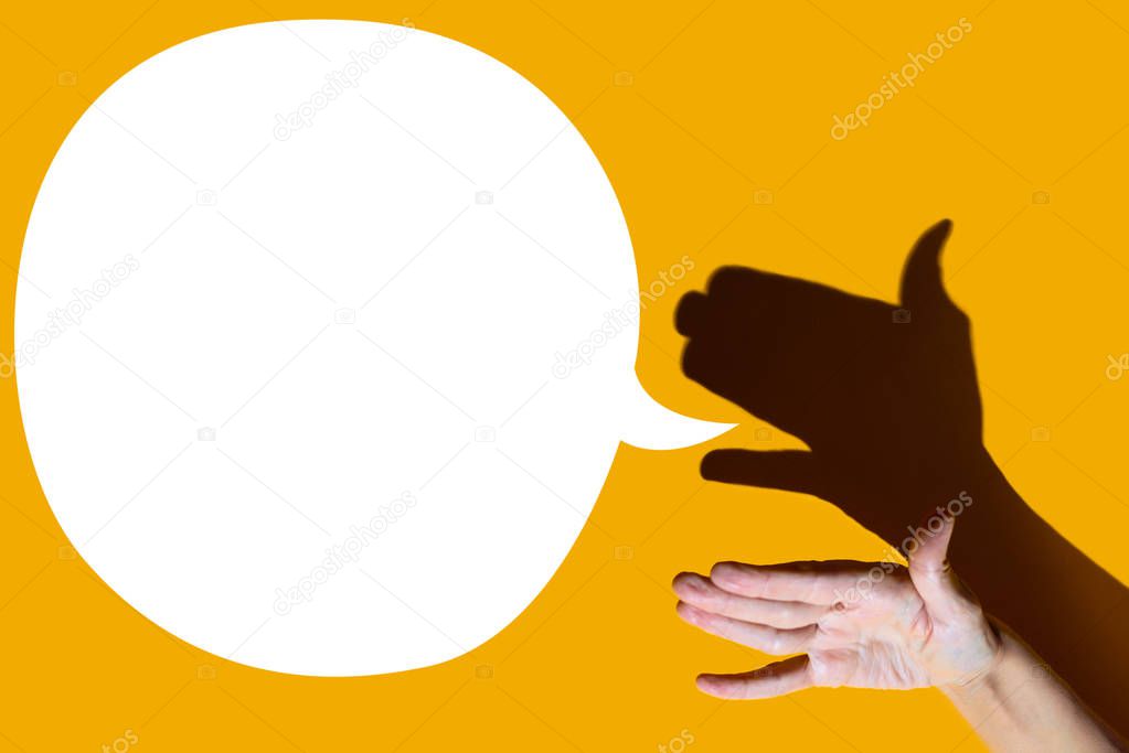 shadow theater. hand shows dog with open a mouth. She's talking on yellow background