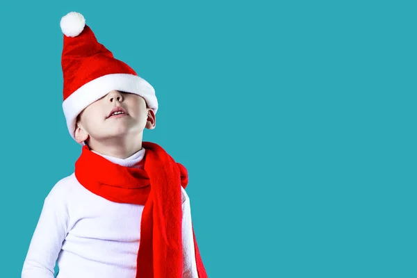 merry little Santa\'s hat fell down over his eyes. A red scarf is tied around his neck. On a blue background