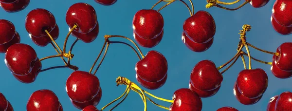 Ayna üzerinde mavi gökyüzünü yansıtan kiraz kirazlarından oluşan parlak burgundy meyveleri serpintisi. Yaz konsepti.