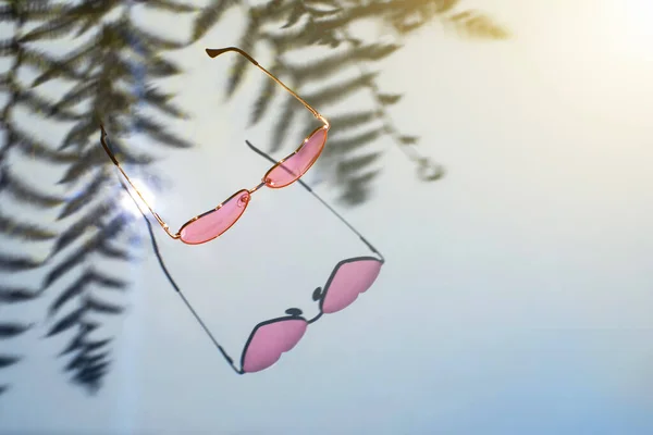 Pink hjerte briller med palme skygger på en blå baggrund. - Stock-foto