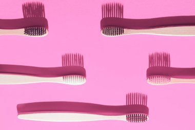Pembe arka planda gölgeli tahta diş fırçaları. Diş Konsepti