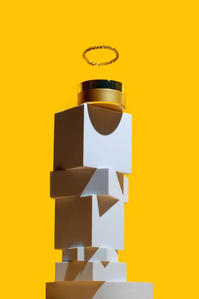 Guldansigtscreme med en glorie som en gud, på et tårn af geometriske former, på en lys gul baggrund - Stock-foto