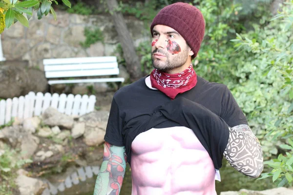 close-up portrait of handsome young man with false tattoos in park