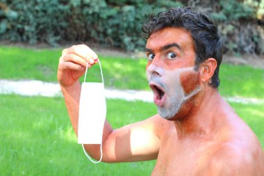 Tıbbi maske şeklinde bronzlaşmış bronz tenli genç adamın yakın plan portresi.