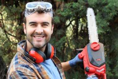 Ormanda testereyle ağaç kesen adam.